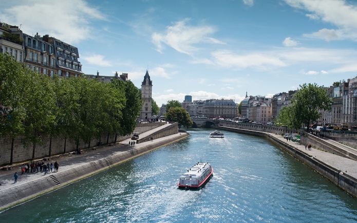 Seine River cruise boat passing under a bridge in Paris with cityscape views.