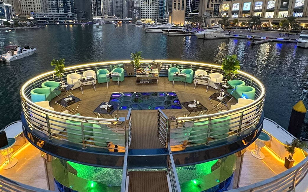 Lotus Mega Yacht deck with seating and tables, Dubai Marina in the background.