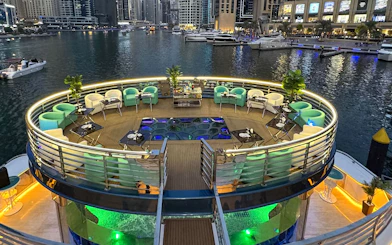 Lotus Mega Yacht deck with seating and tables, Dubai Marina in the background.