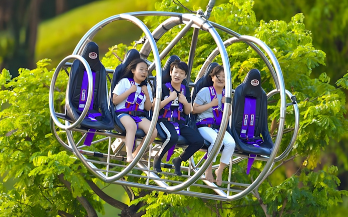 Visitors enjoying the Slingshot ride in Singapore amidst lush greenery.