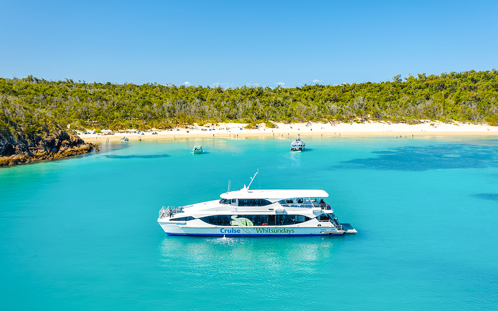 Boat near Whitehaven Beach, Whitsundays, with Great Barrier Reef backdrop.