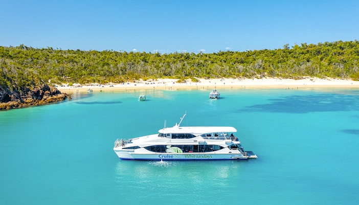 Boat near Whitehaven Beach, Whitsundays, with Great Barrier Reef backdrop.