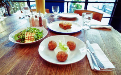 Three Greek dishes on a table: fried Saganaki cheese, moussaka, and zucchini fritters.