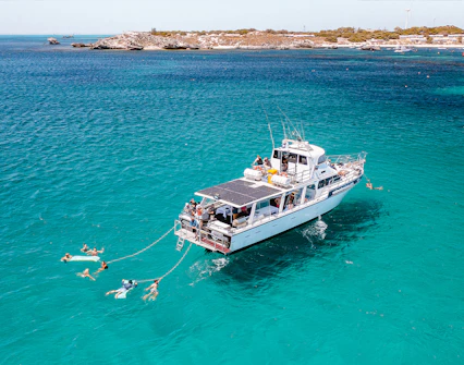 Luxury boat with swimmers in turquoise waters near Rottnest Island.