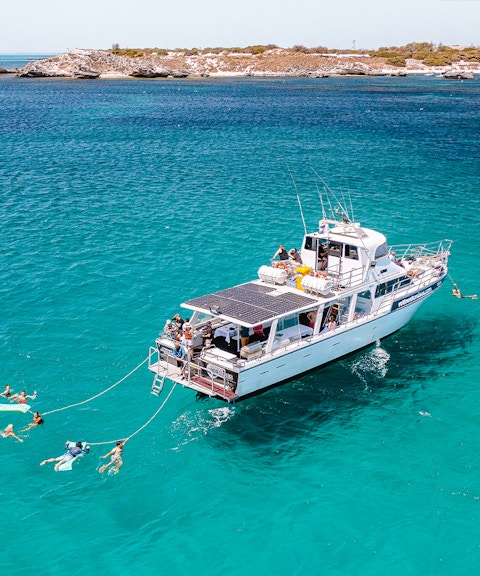 Luxury boat with swimmers in turquoise waters near Rottnest Island.