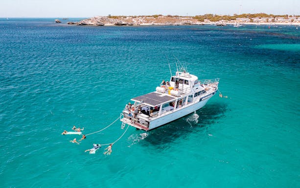 Luxury boat with swimmers in turquoise waters near Rottnest Island.