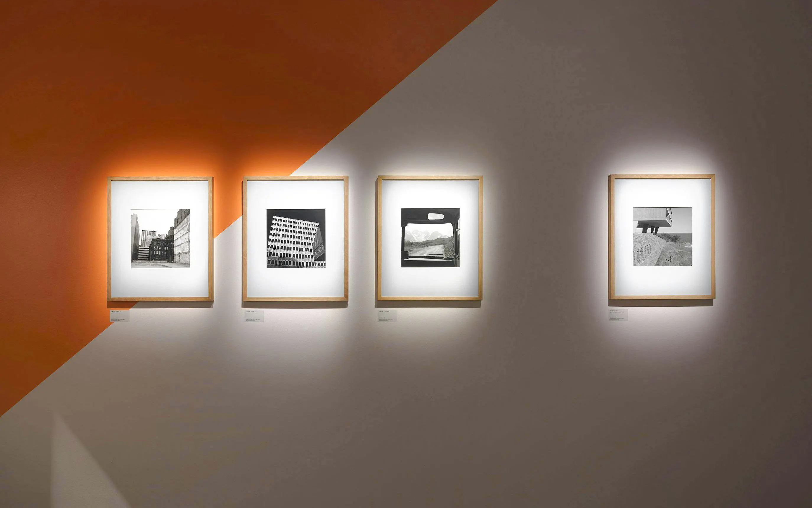 Black and white photographs displayed on an orange and white wall at Fotografiska Berlin exhibit.