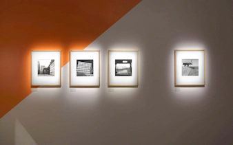 Black and white photographs displayed on an orange and white wall at Fotografiska Berlin exhibit.