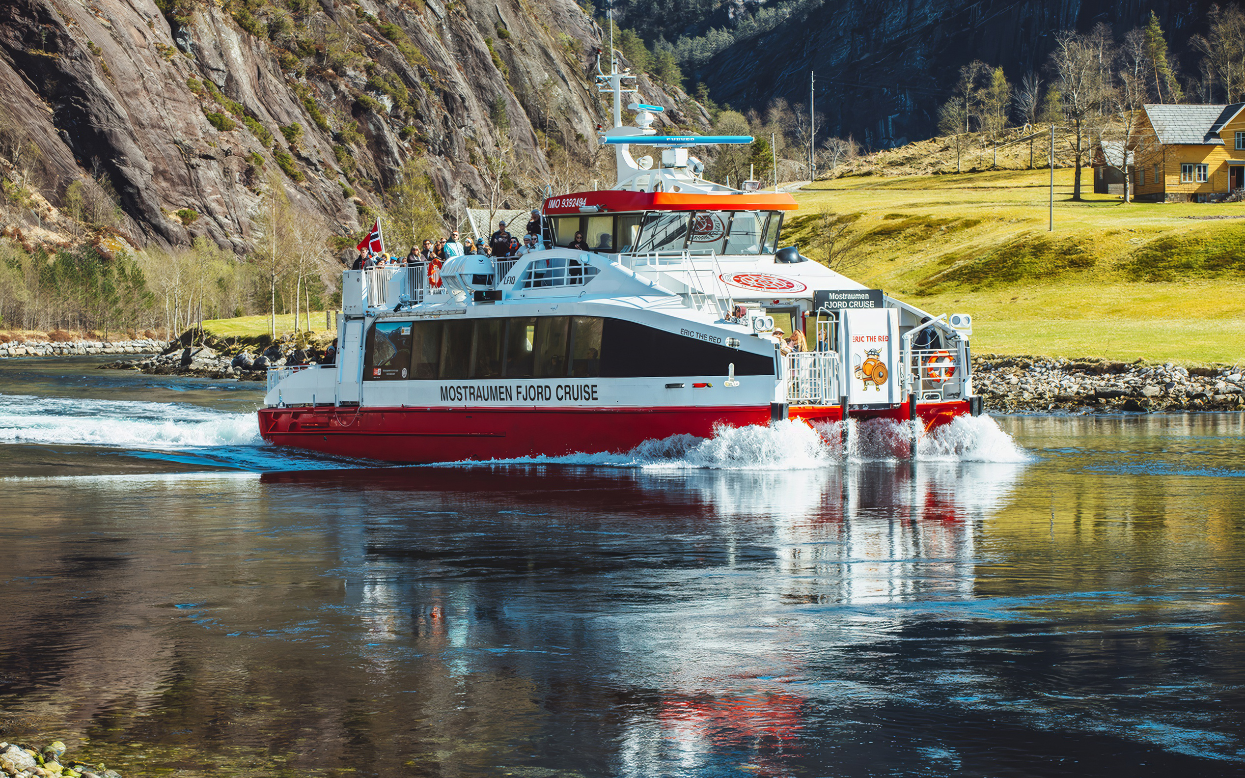 Cruise boat on Mostraumen Fjord near Bergen with passengers enjoying scenic views.