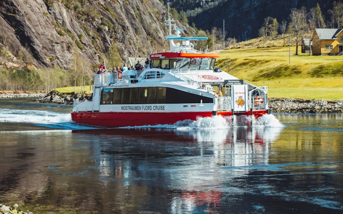 Cruise boat on Mostraumen Fjord near Bergen with passengers enjoying scenic views.