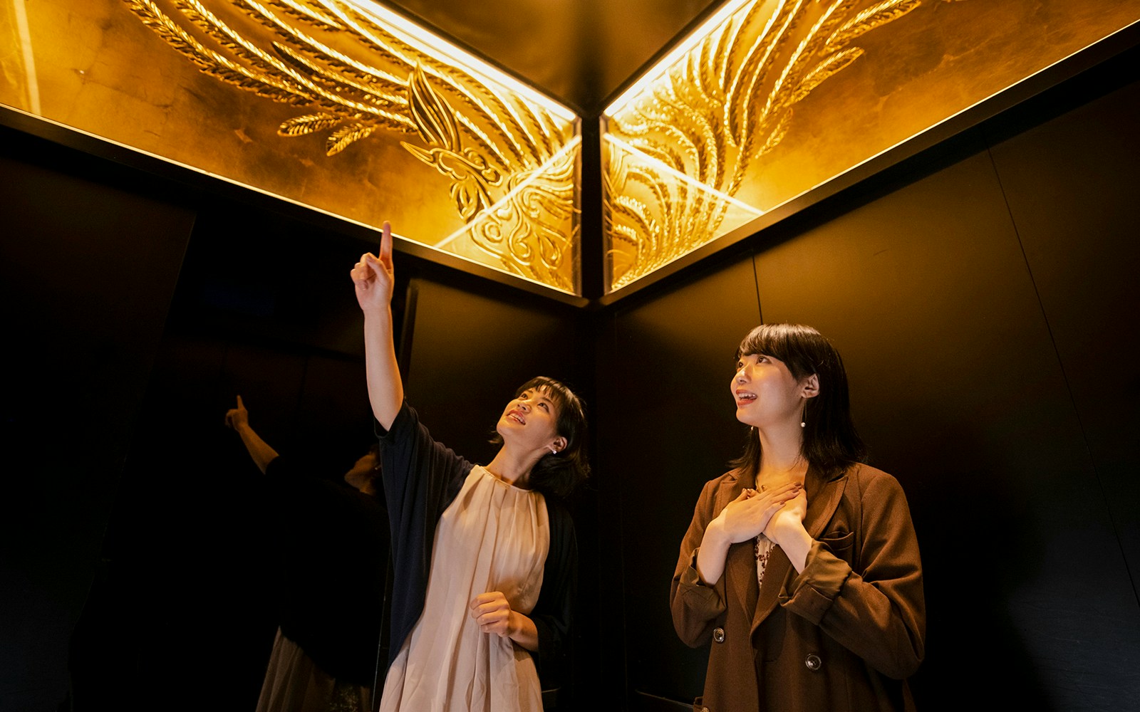 Women admiring ornate ceiling in Tokyo Skytree elevator.