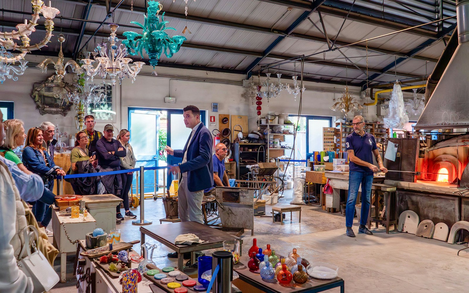 Murano artisan shaping glass with tools in a Venice workshop.