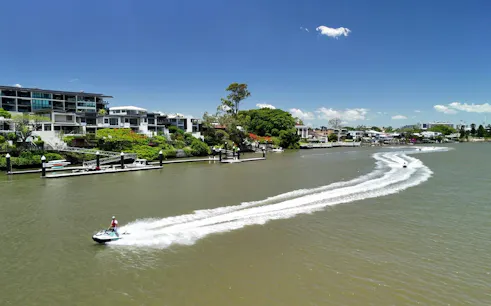 Jet ski on Brisbane River with cityscape in background, part of guided tour.