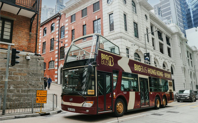 Hop-on hop-off bus in Hong Kong near historic buildings, part of Victoria Harbor ferry tour.