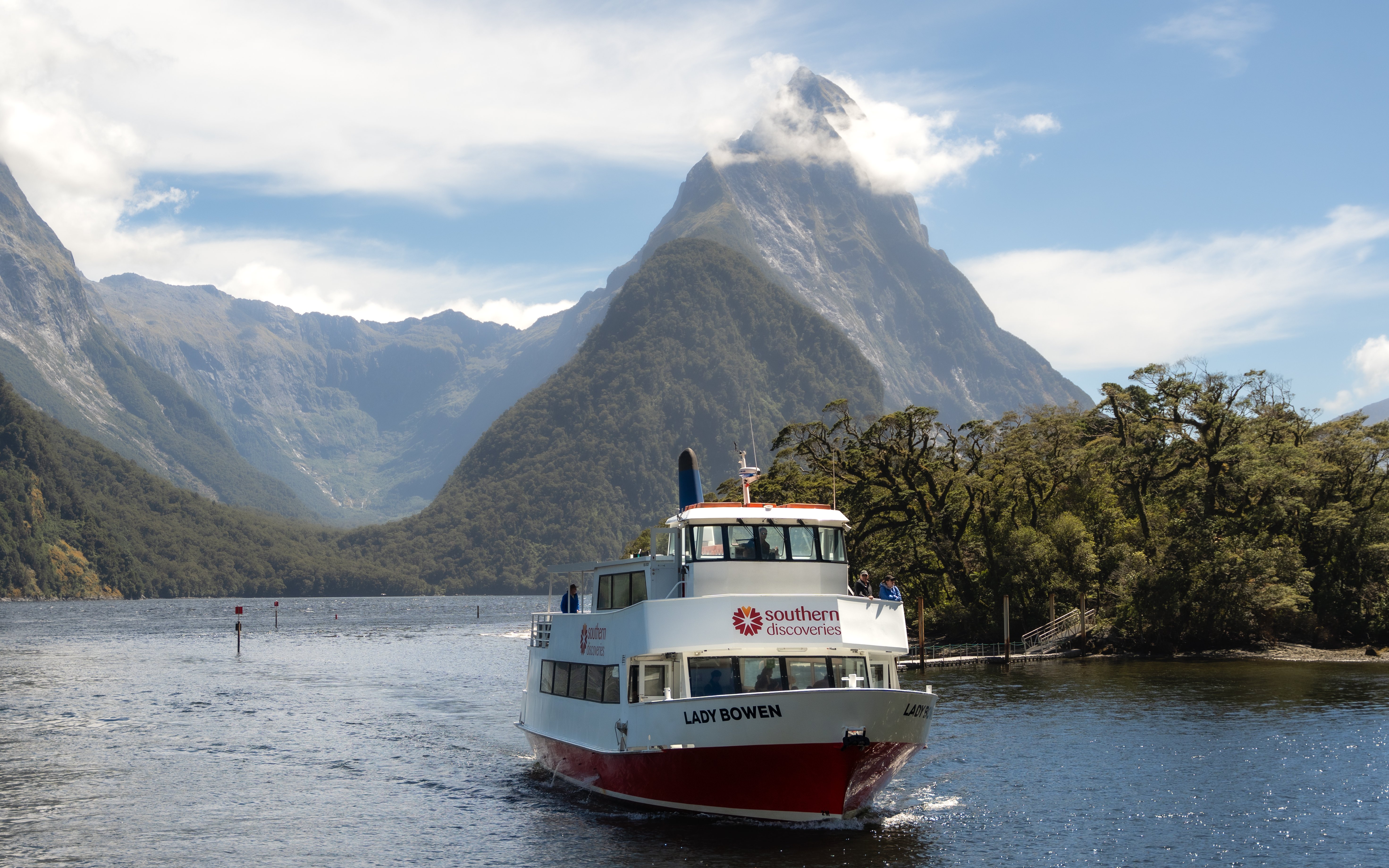 Cruise boat on Milford Sound with Mitre Peak in the background, New Zealand.