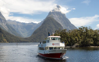 Cruise boat on Milford Sound with Mitre Peak in the background, New Zealand.