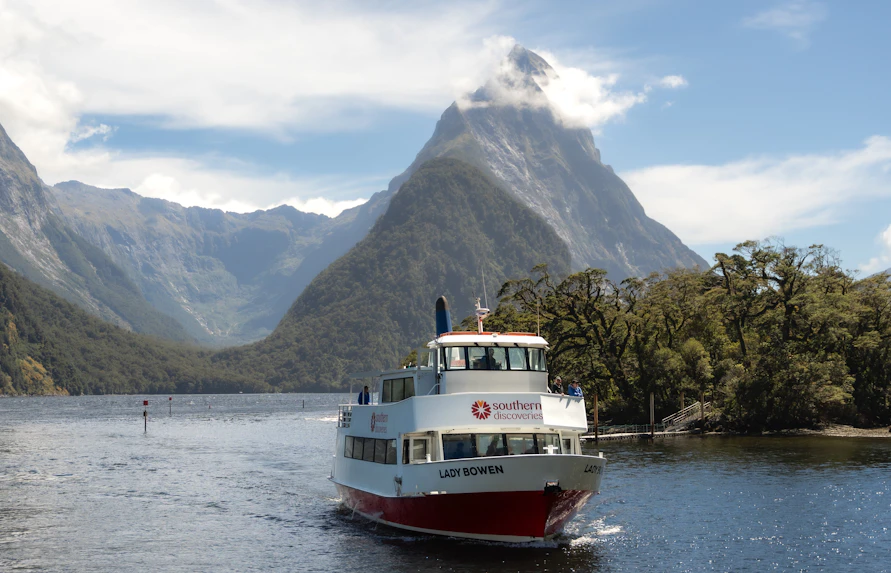 Cruise boat on Milford Sound with Mitre Peak in the background, New Zealand.