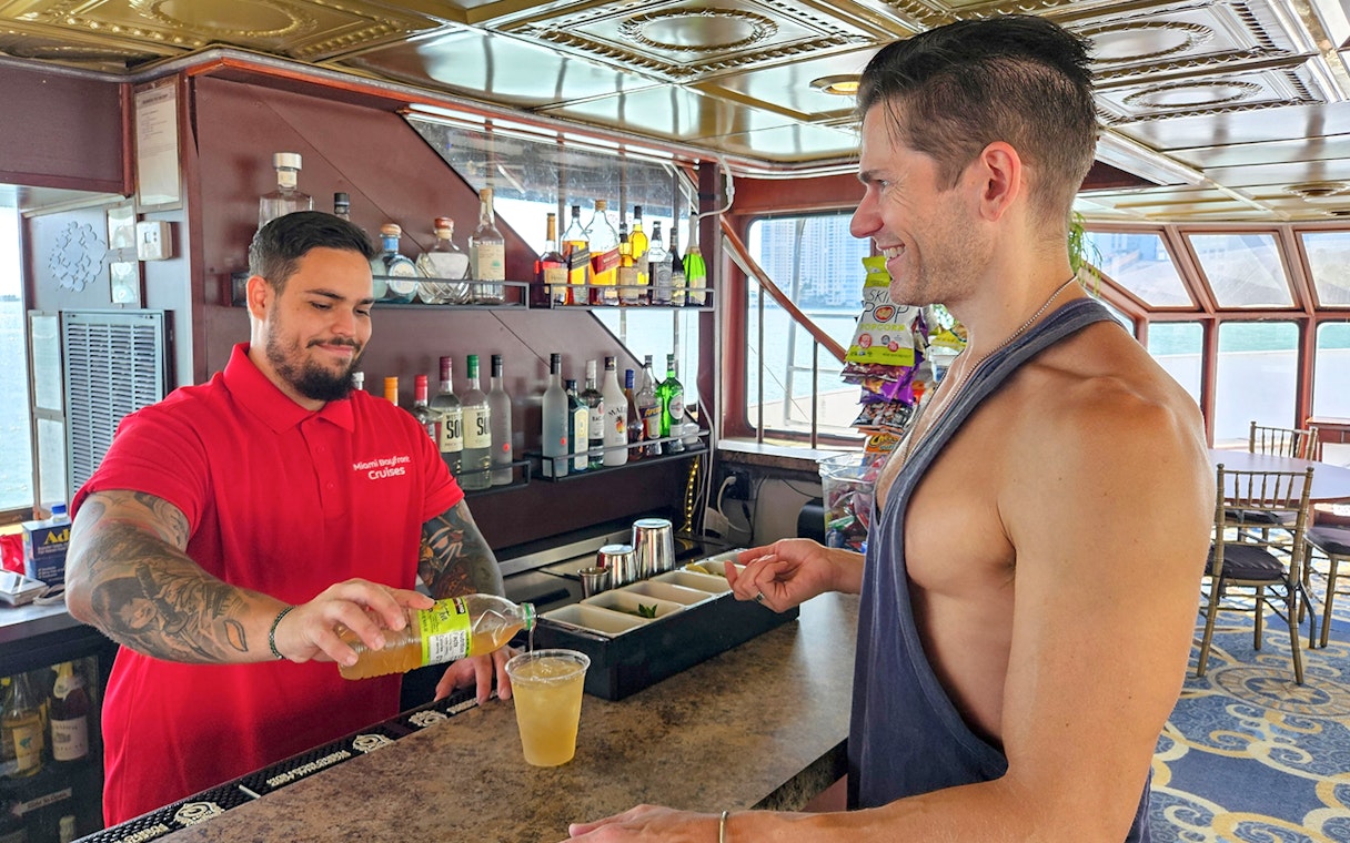 Bartender serving a drink to a guest on a Miami luxury yacht cruise.