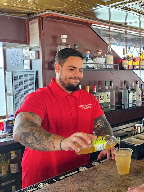 Bartender serving a drink to a guest on a Miami luxury yacht cruise.