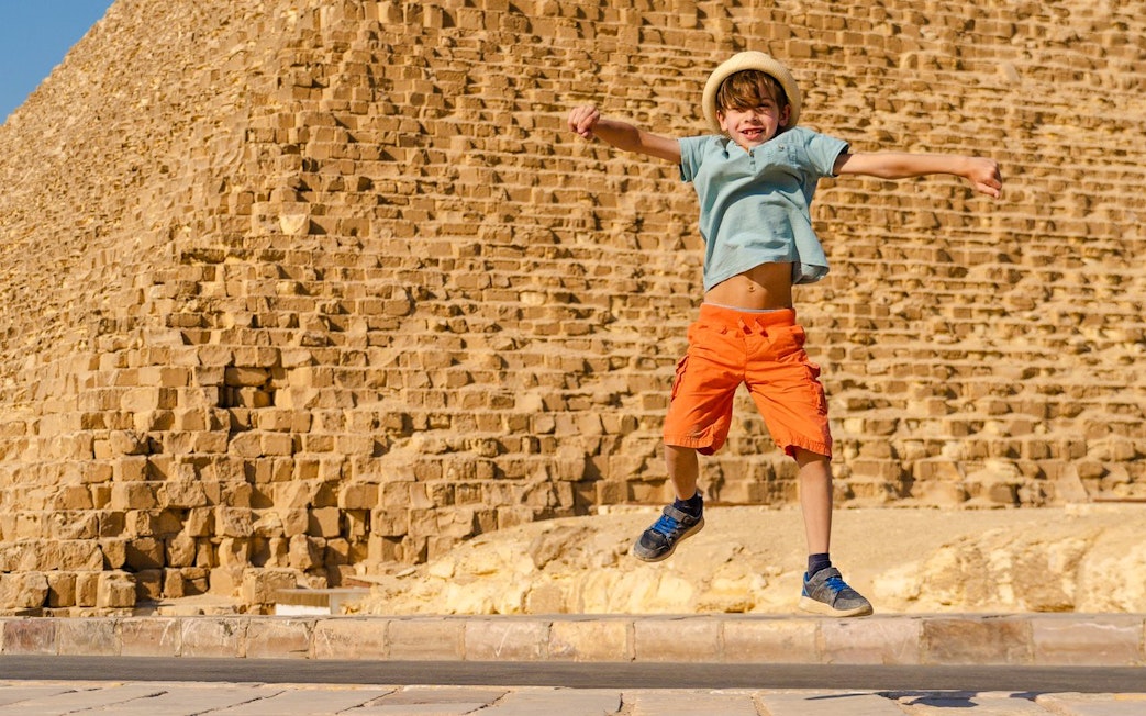 Child jumping in front of the Pyramid of Giza, Egypt.