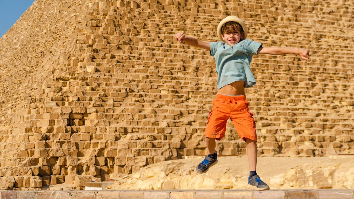 Child jumping in front of the Pyramid of Giza, Egypt.