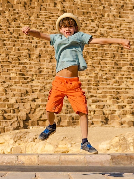 Child jumping in front of the Pyramid of Giza, Egypt.