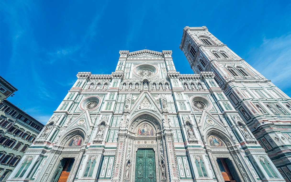 Duomo Florence facade with bell tower under blue sky.