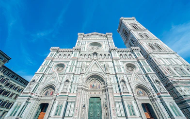 Duomo Florence facade with bell tower under blue sky.