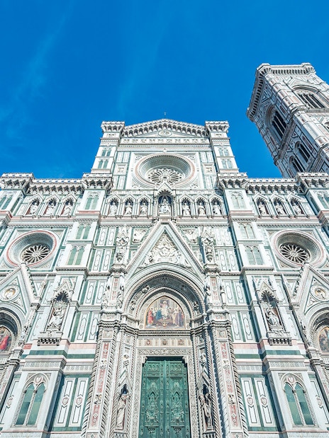 Duomo Florence facade with bell tower under blue sky.