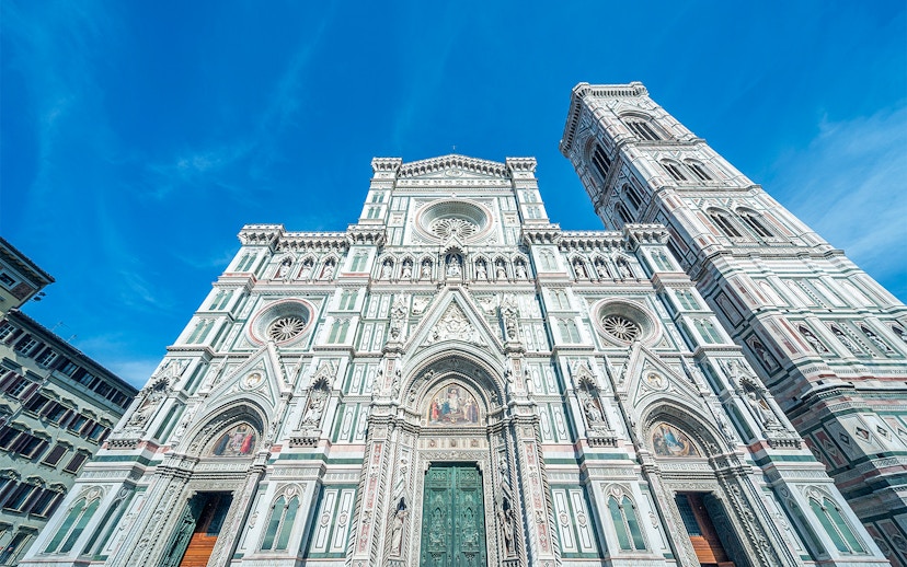 Duomo Florence facade with bell tower under blue sky.