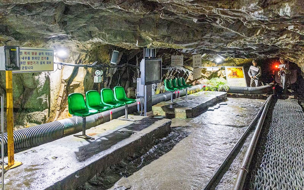DMZ 2nd Tunnel interior with green seats and informational signs on the Fullday Cliffside Path Tour.