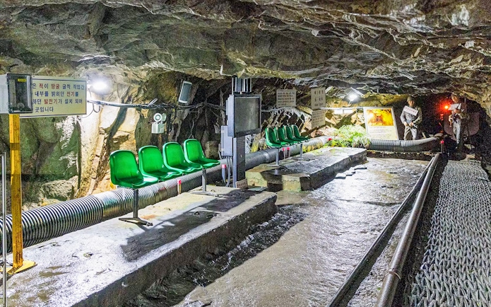 DMZ 2nd Tunnel interior with green seats and informational signs on the Fullday Cliffside Path Tour.