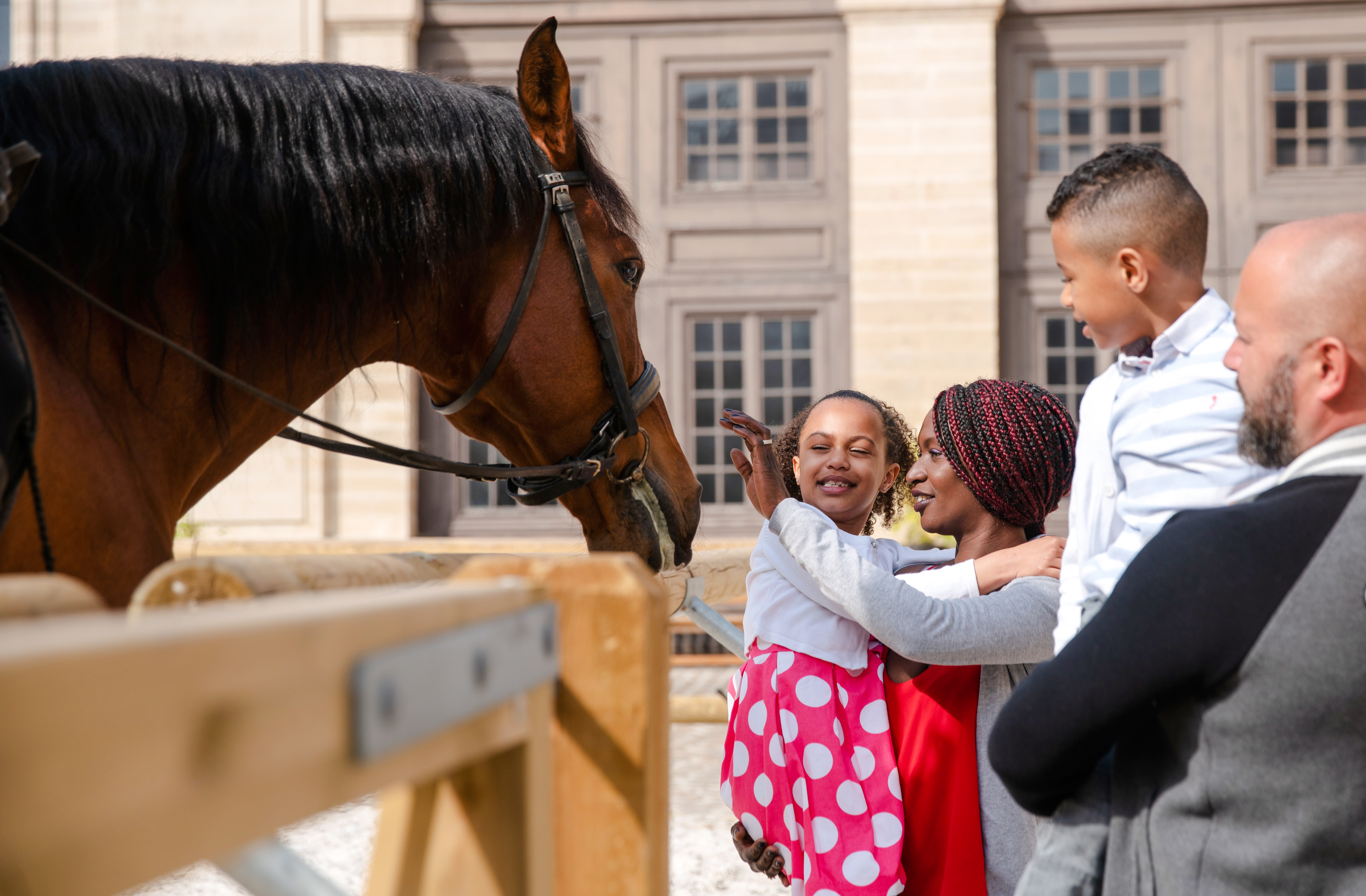 Family interacting with a horse at Chateau of Chantilly, France.
