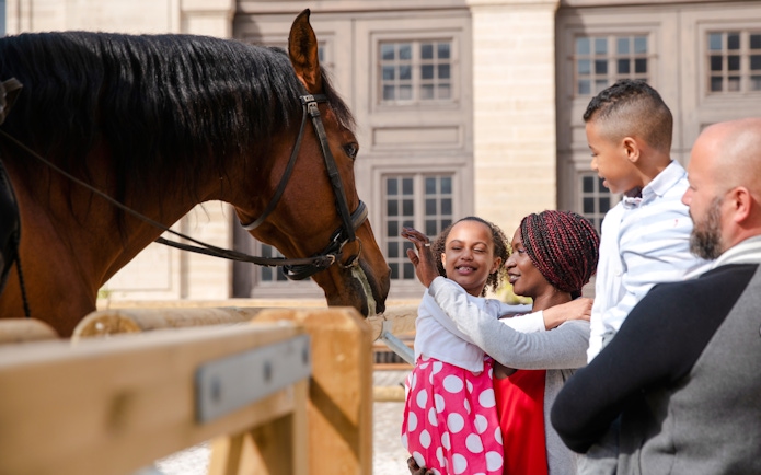 Family interacting with a horse at Chateau of Chantilly, France.