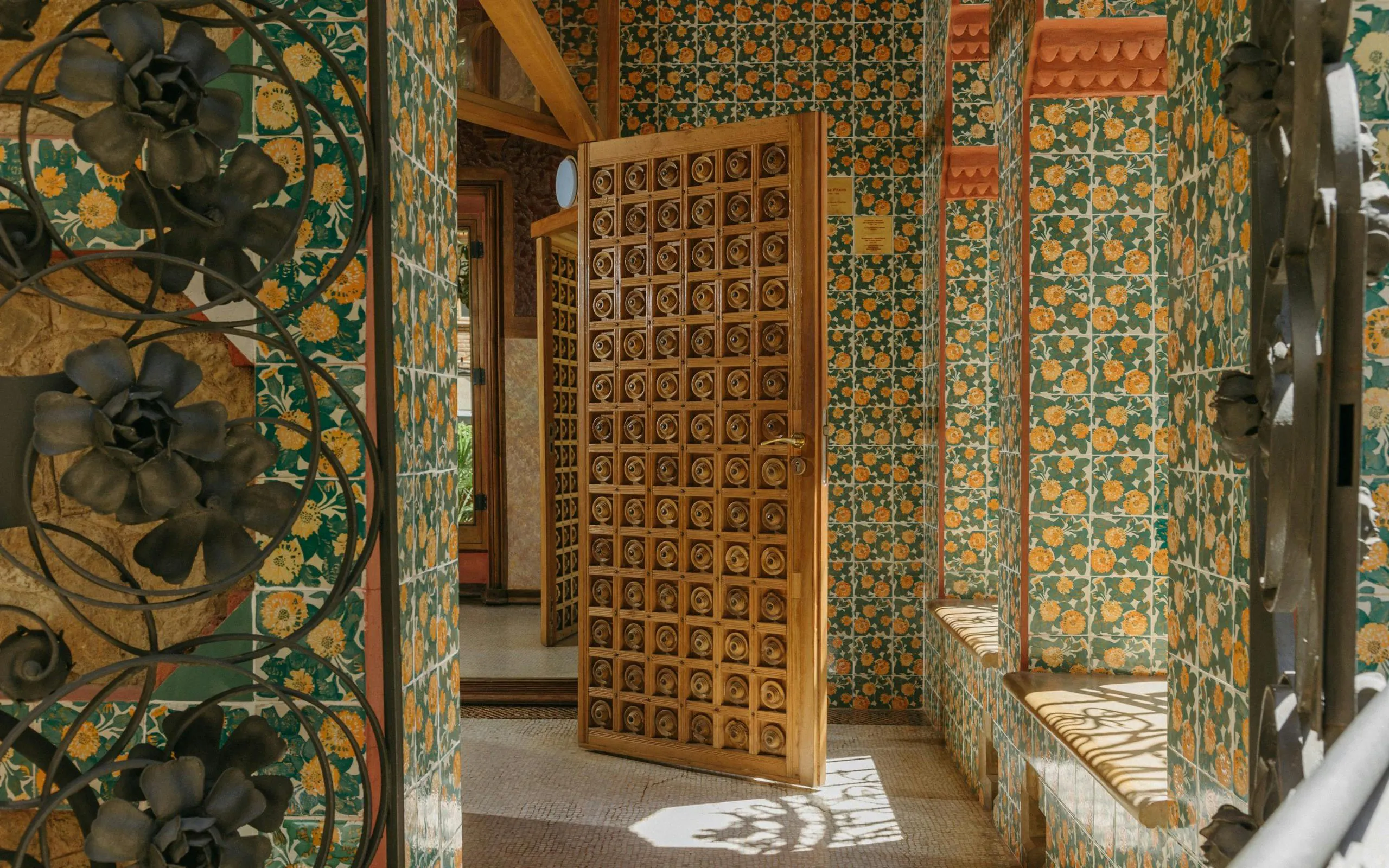 Casa Vicens interior with floral tiles and ornate wooden door in Barcelona.
