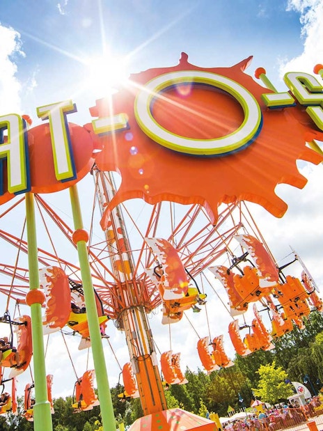Splat-O-Sphere ride with orange swings and green poles under a sunny sky.
