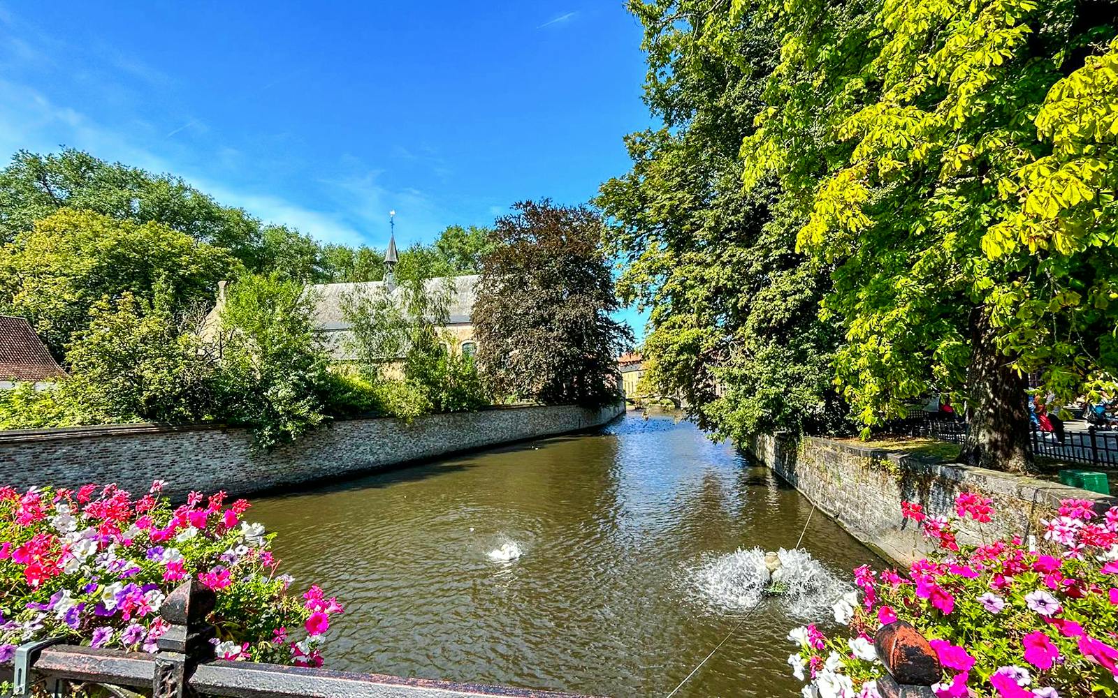 Canal view with flowers and trees in Bruges, Belgium.