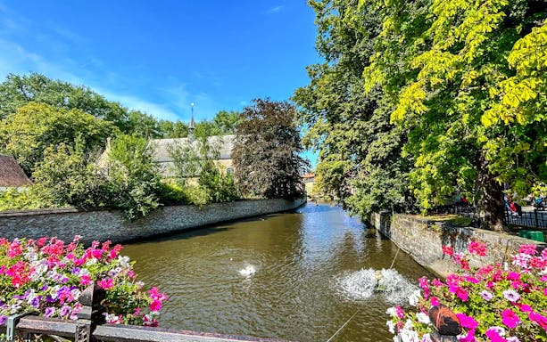 Canal view with flowers and trees in Bruges, Belgium.