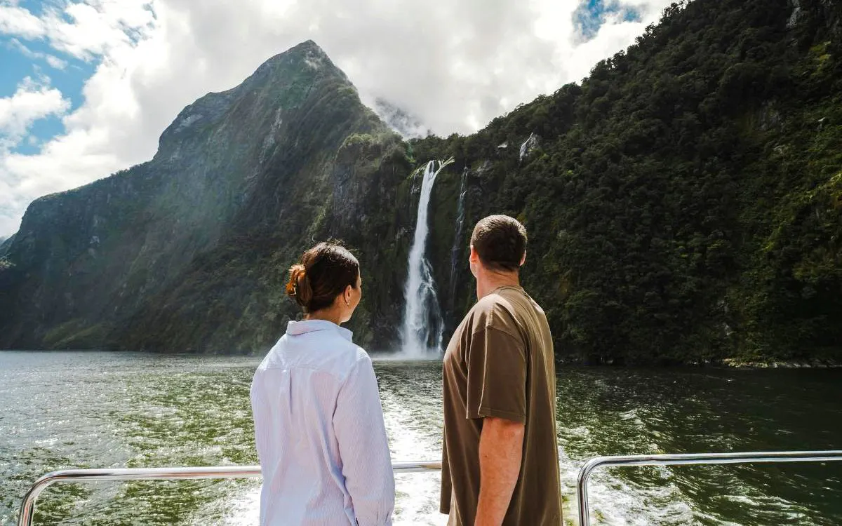 Tourists viewing waterfall on Milford Sound cruise, New Zealand.