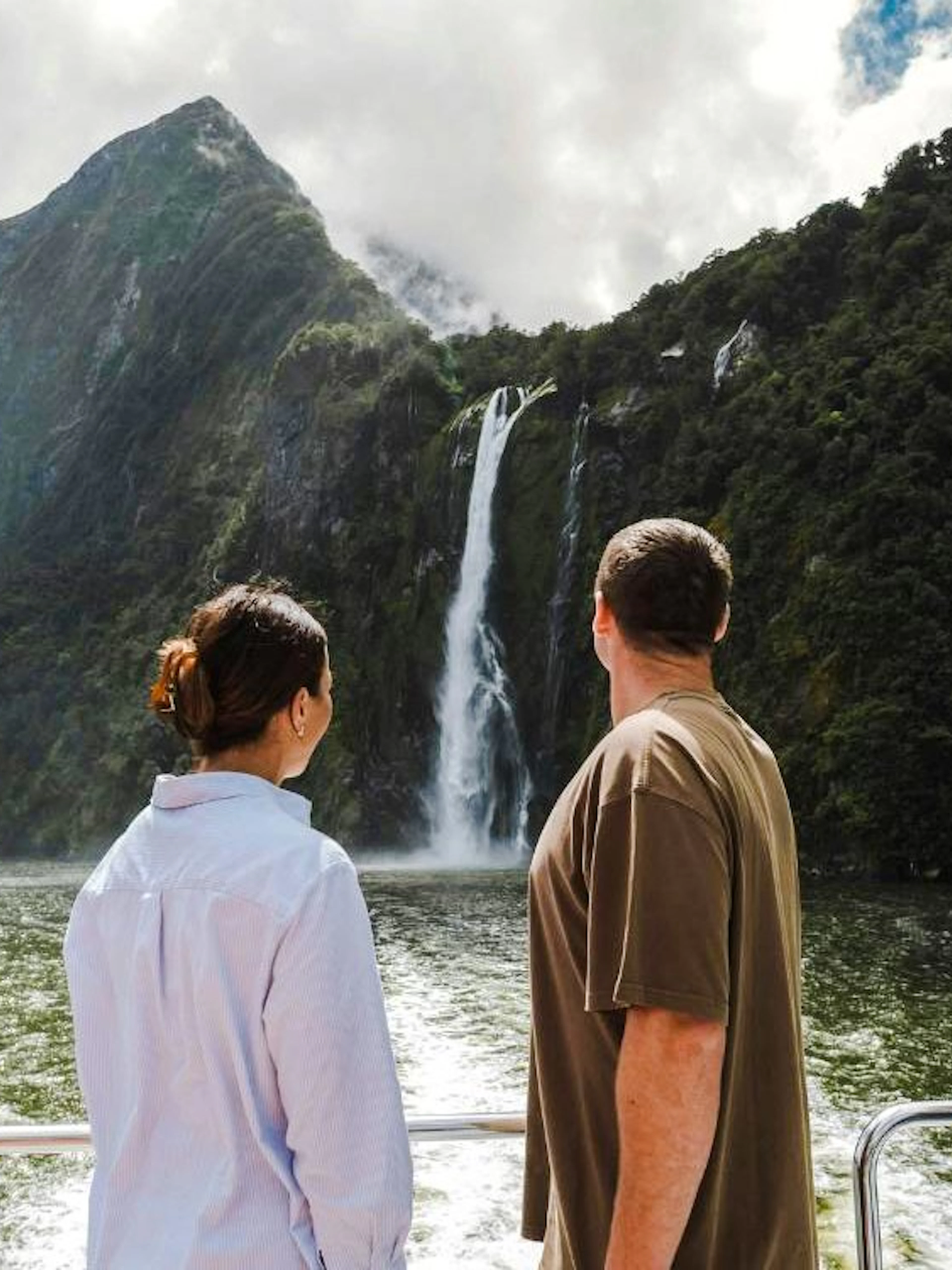 Tourists viewing waterfall on Milford Sound cruise, New Zealand.