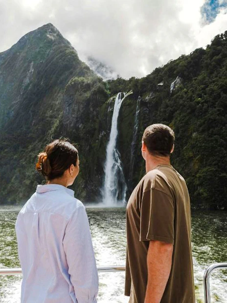 Tourists viewing waterfall on Milford Sound cruise, New Zealand.