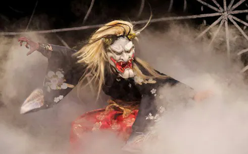 Kagura performer in traditional costume and mask during Hiroshima show.