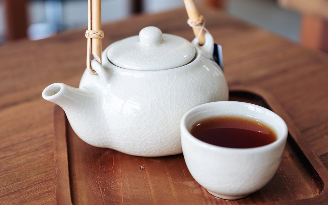 Japanese teapot and cup with tea on a wooden tray.