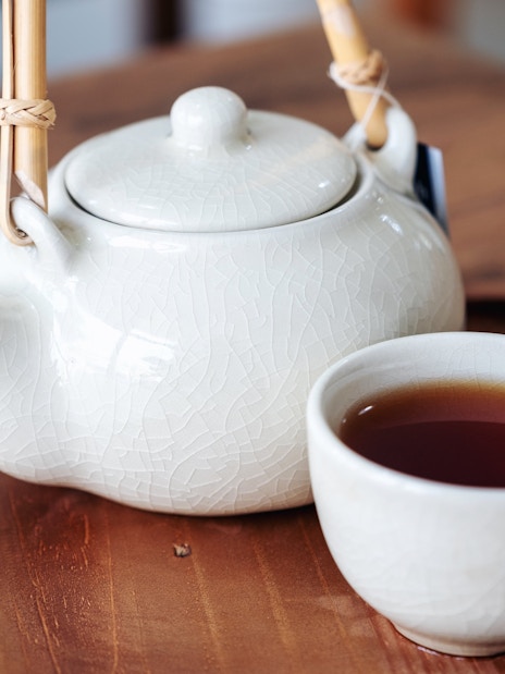 Japanese teapot and cup with tea on a wooden tray.