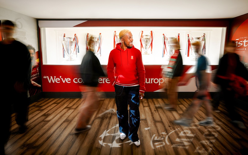 Visitors exploring Liverpool Football Club Museum with European trophies displayed.
