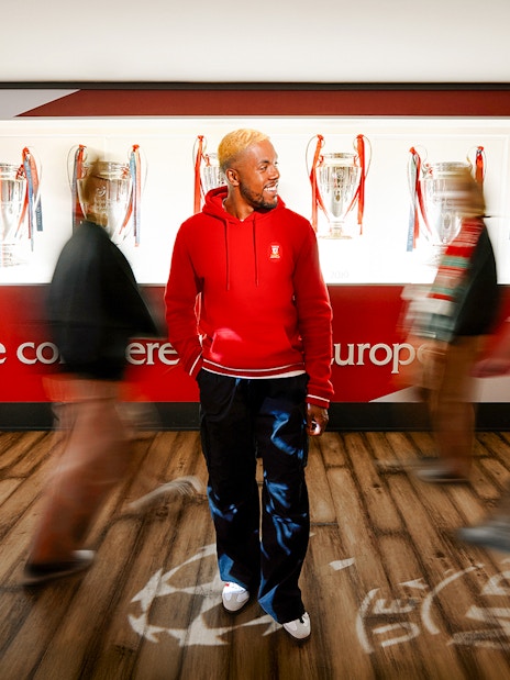 Visitors exploring Liverpool Football Club Museum with European trophies displayed.