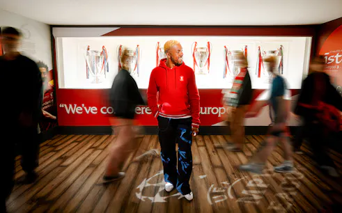Visitors exploring Liverpool Football Club Museum with European trophies displayed.