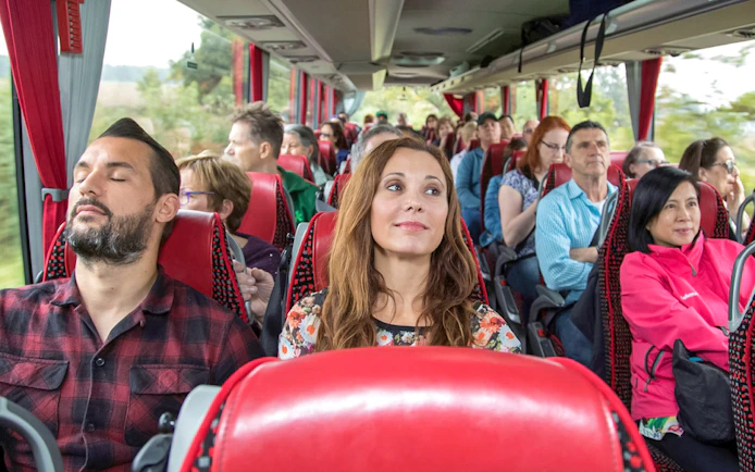 Tourists seated on an air-conditioned coach bus.