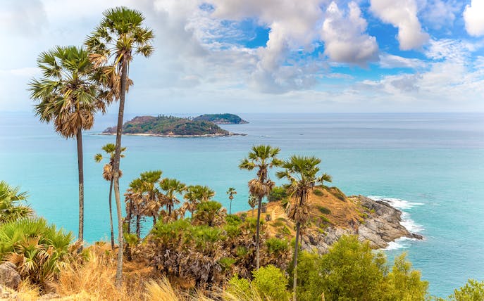 Promthep Cape Thailand with palm trees overlooking the ocean and rocky coastline.
