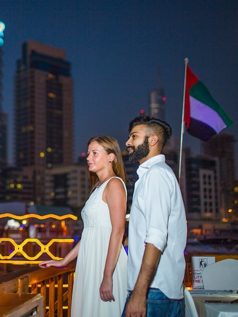 Couple enjoying Marina skyline from Alexandra VIP Dhow Cruise in Dubai.